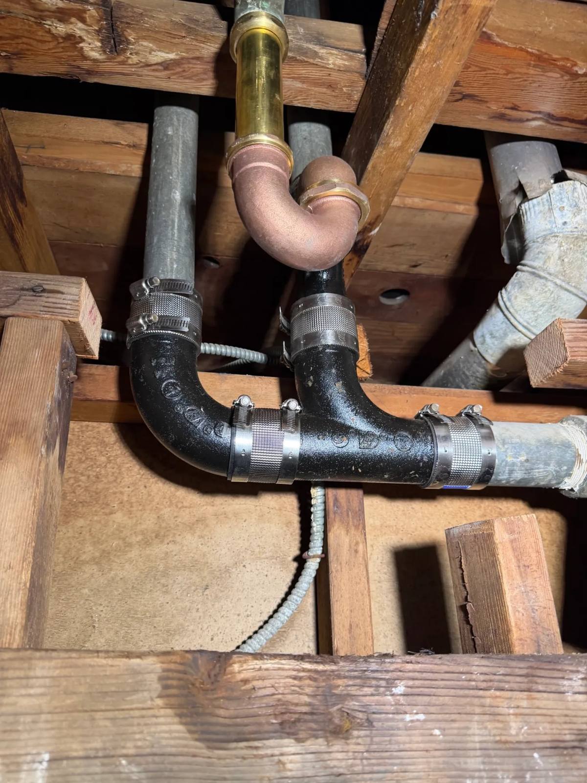 New cast iron drain pipe installed in the joists above a bathroom — drain cleaning in Westchester