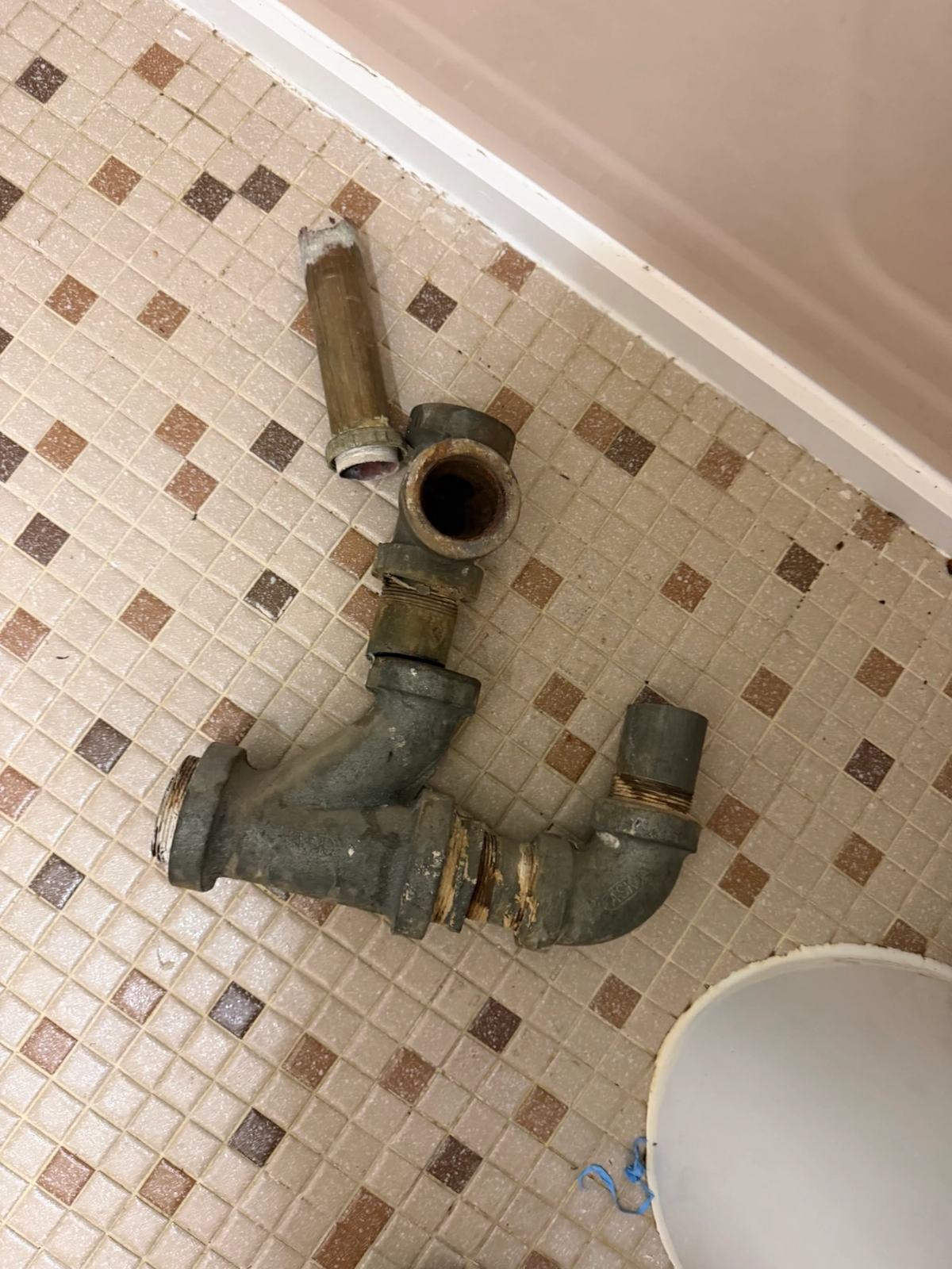 Corroded galvanized waste pipe lifted out of a bathroom floor — clogged toilet repair and bathroom drain work in Westchester