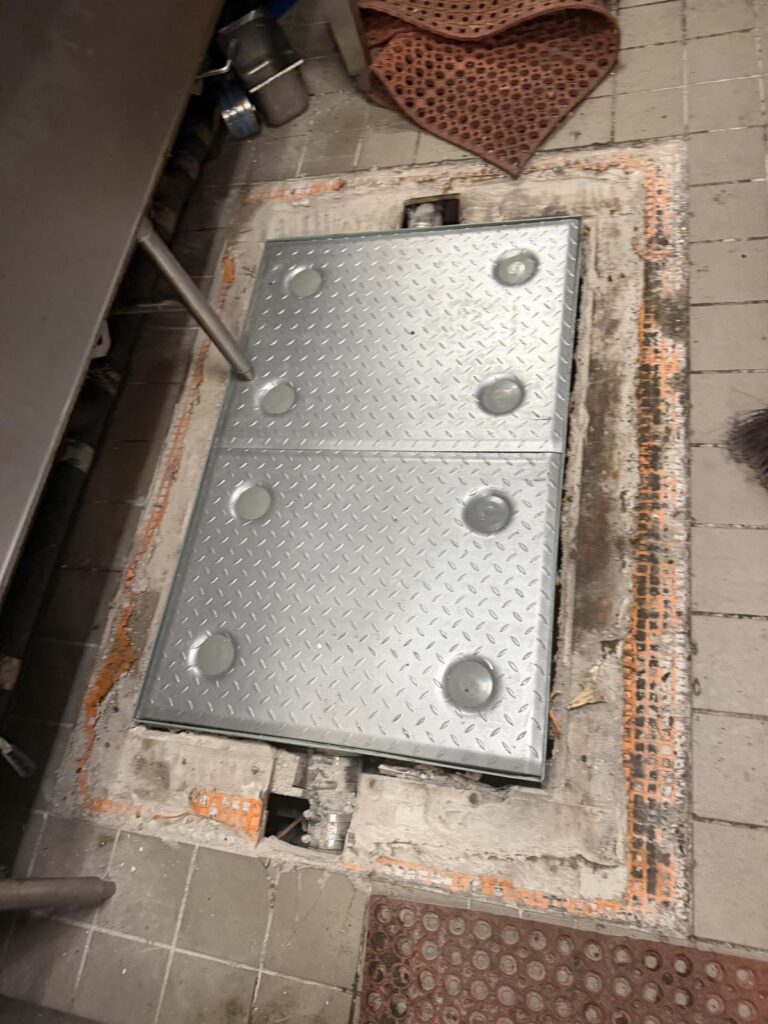 The finished commercial kitchen floor hatch, diamond plate and flush with the tile