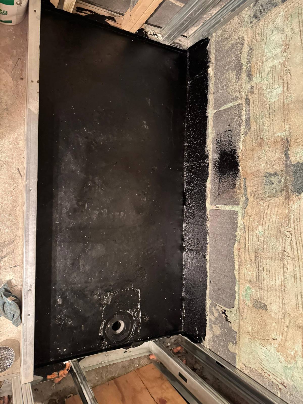 A shower base sealed with a waterproof coating out to the walls, with the drain in place, before tiling